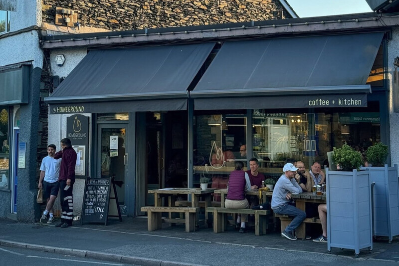 People sitting at benches under the awnings outside Homeground Café, Windermere
