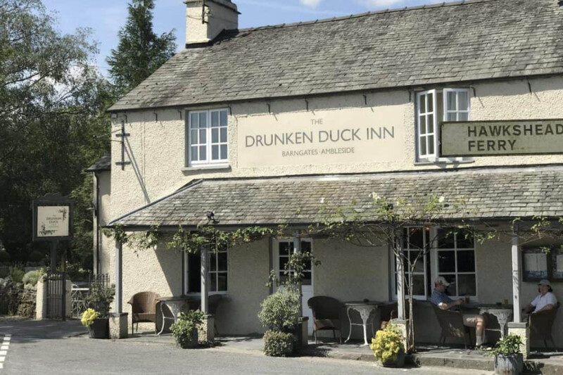 Exterior of The Drunken Duck Inn with people sitting outside, near Ambleside