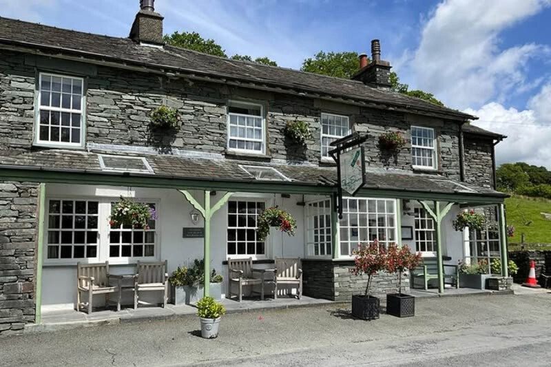 Slate-built exterior with hanging baskets at The Three Shires Inn, Little Langdale