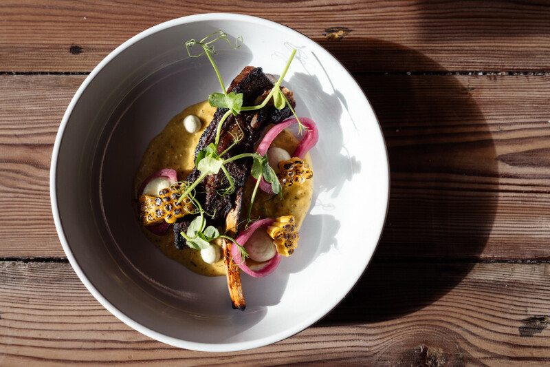 Plated dish garnished with pea shoots on a wooden table at The Yan, Grasmere